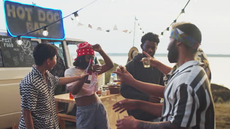 Group-of-Happy-Friends-Dancing-and-Drinking-at-Summer-Festival